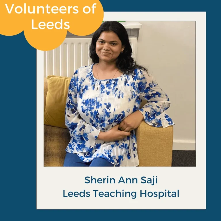 Sherin Ann Saji smiles on a yellow sofa in Leeds, volunteering with Leeds Teaching Hospital for Volunteers of Leeds.